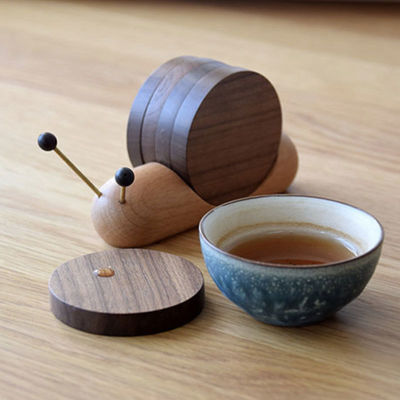 Des chaussettes à roulettes noires créatives en forme d'escargot, une tasse isolante en bois, une soucoupe de style moderne.