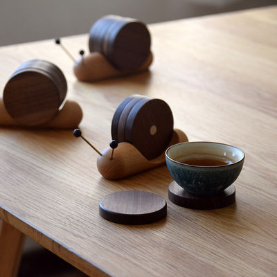 Des chaussettes à roulettes noires créatives en forme d'escargot, une tasse isolante en bois, une soucoupe de style moderne.